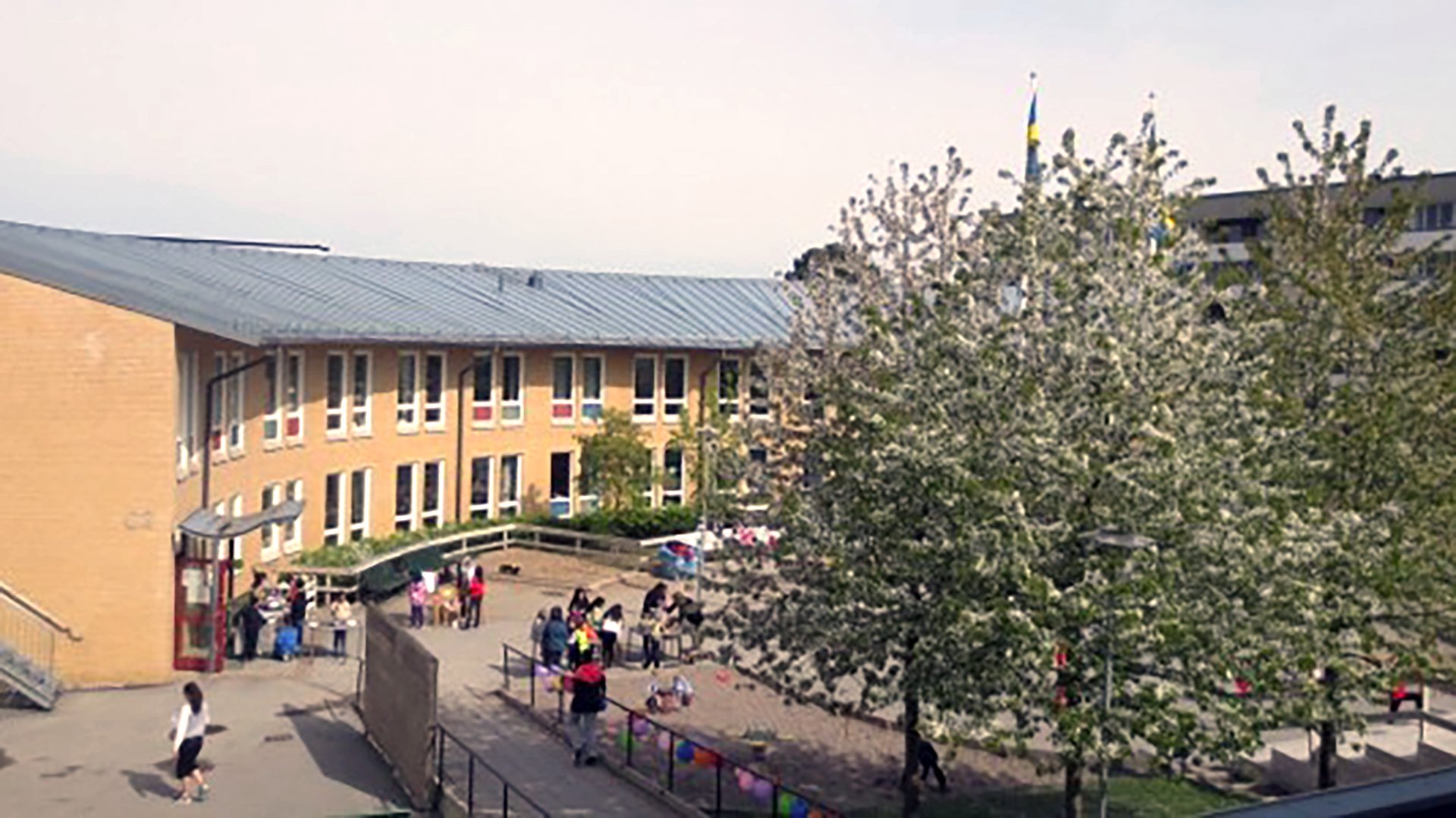 Östbergaskolan med gul fasad och skolgård med lekande barn där Ebab medverkat som Kontrollansvarig enligt PBL