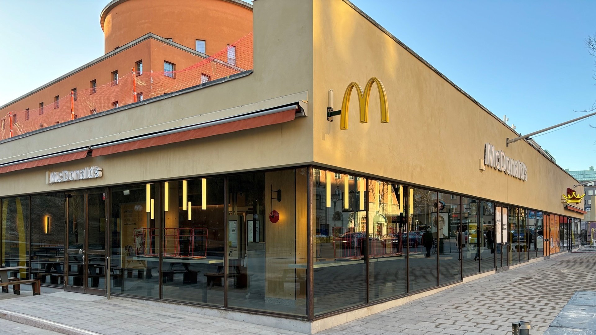 Hörnfasad med gul puts och stora glasfönster med Stockholms stadsbibliotek i bakgrunden. 