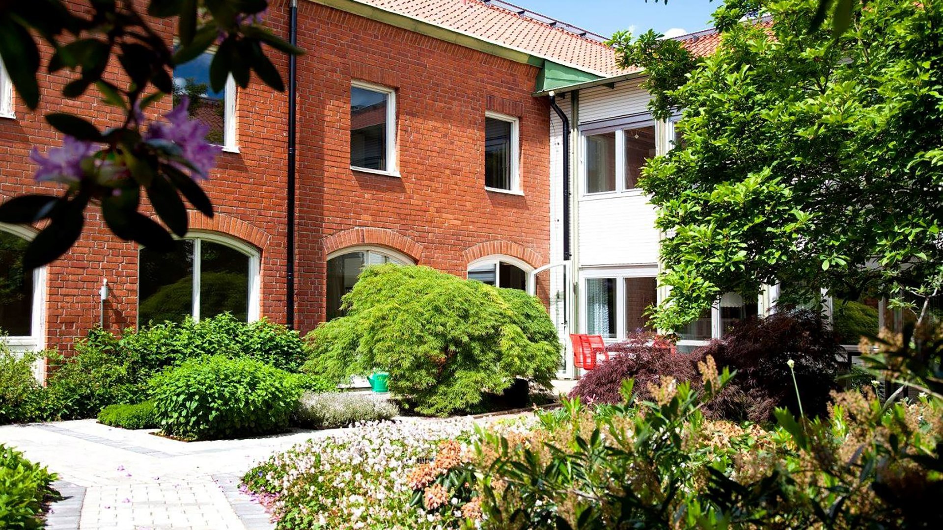 En tegelfasad med en lummig trädgård framför där lokalerna anpassades till intensivvårdsnära rehablilitering.