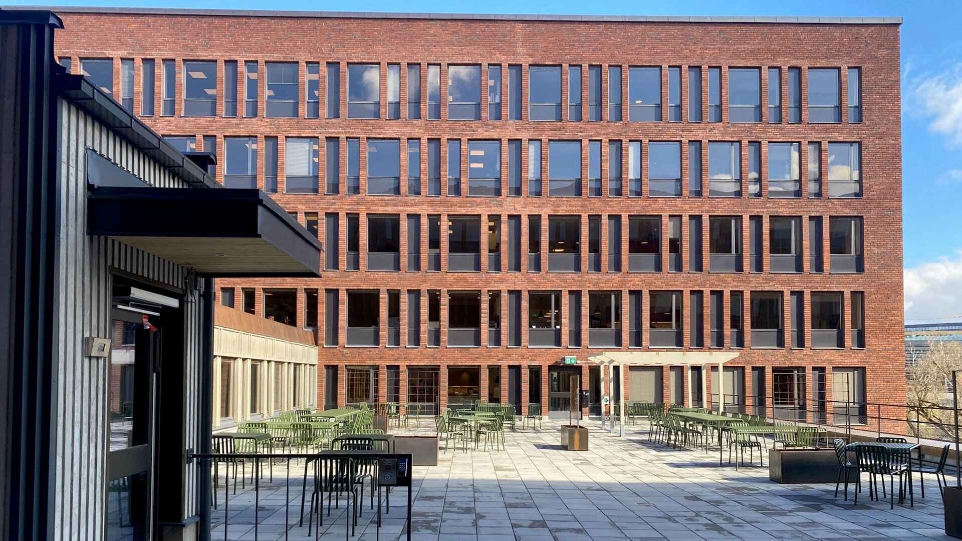 Fasad i rött tegel och glas på Tekniska nämndhuset där Ebab höll i samordning för yttre projekt som omläggning av tak