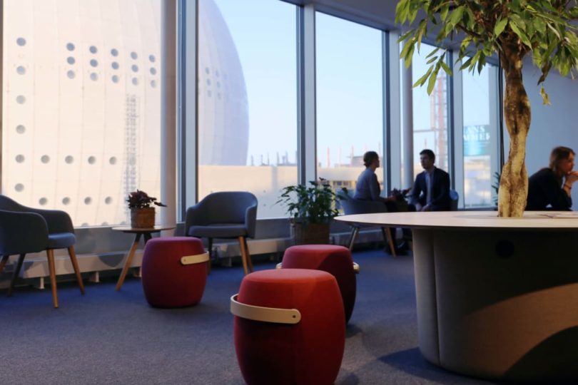 En lounge med sittpuffar i rött med Globen i bakgrunden - invigning av Ebabs kontor i Söderstaden