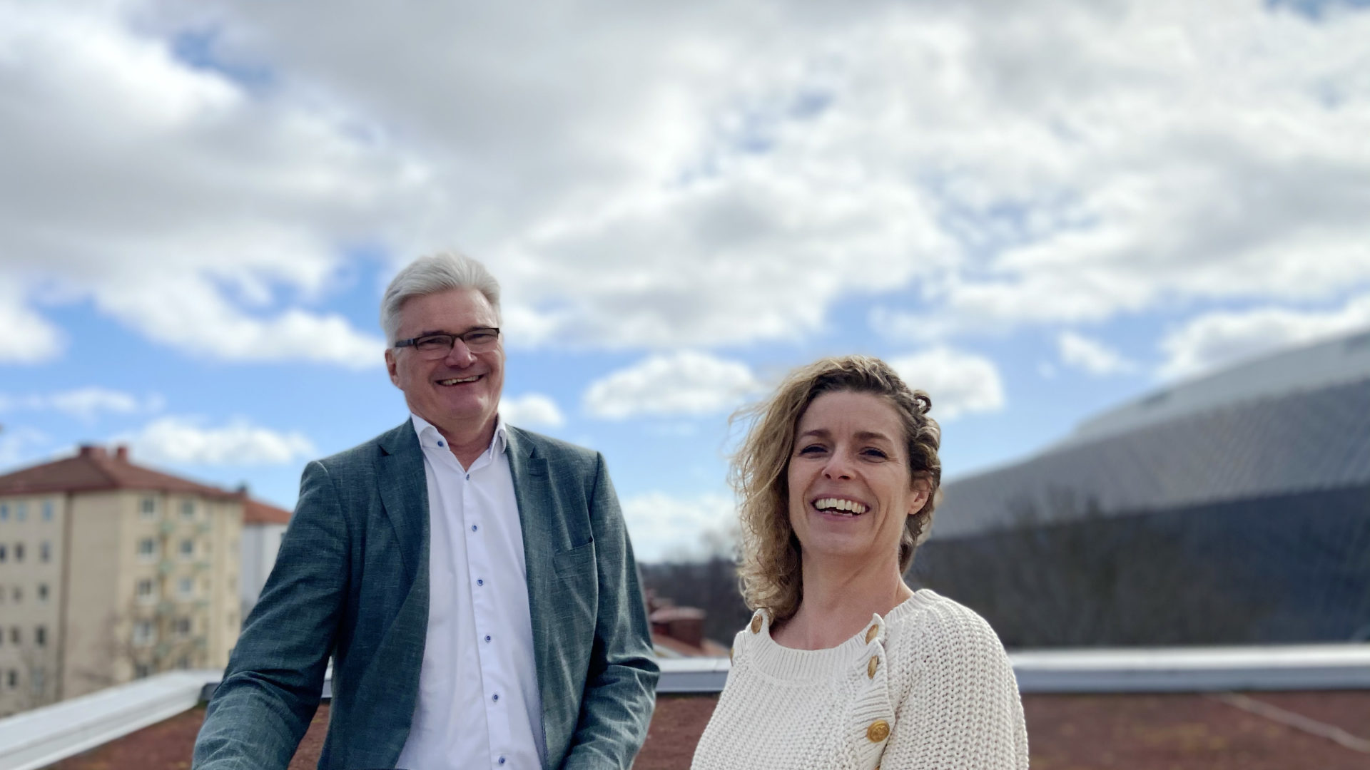 Halvkroppsporträtt med en man och en kvinna på en balkong med en molnig himmel i bakgrunden. Göran Westerberg och hållbarhetschef Ellinor OIsson.